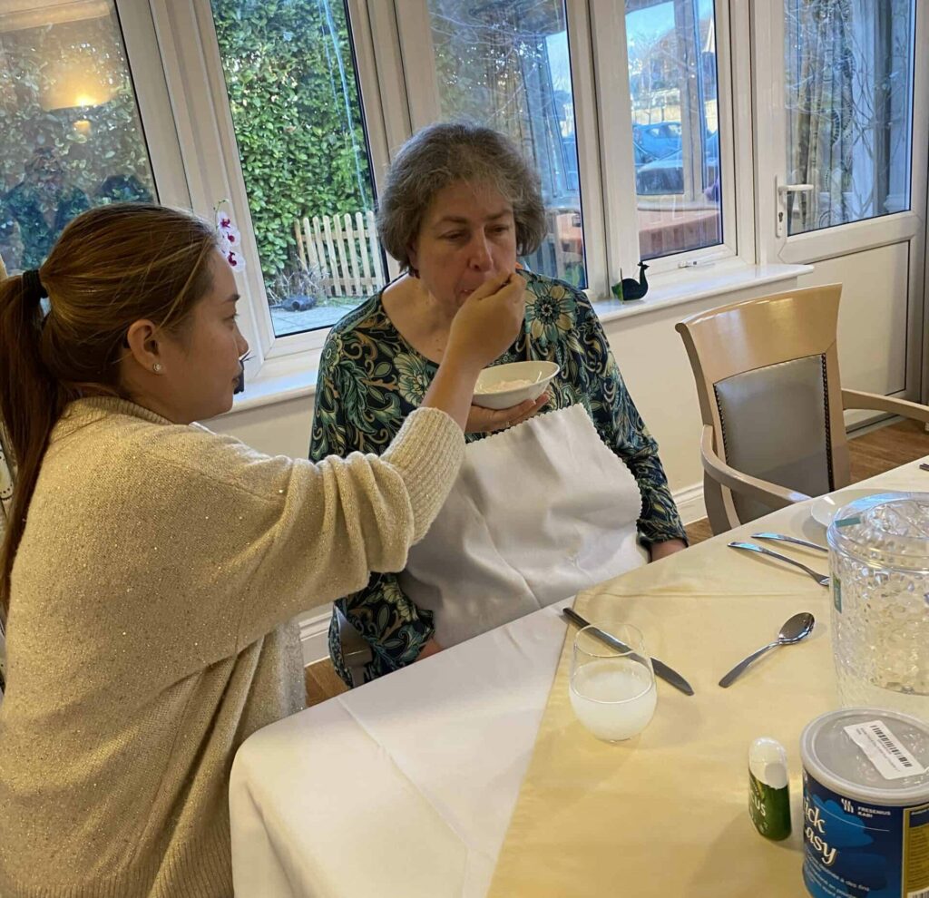 Carer feeds fellow learner at Athena Care Homes during induction training