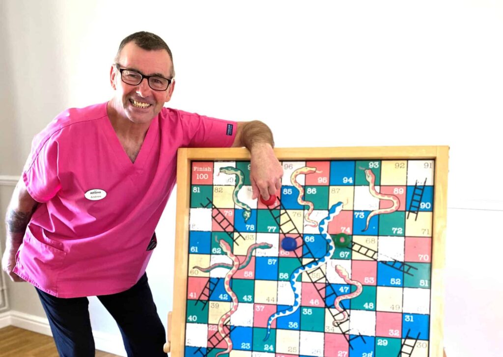 Man in pink tunic with giant snakes and ladders board